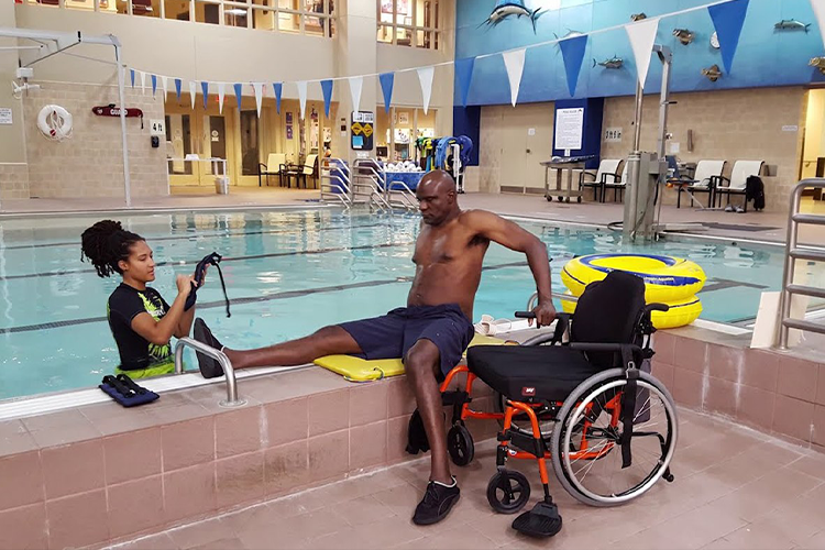 Male sits on side of the Shepherd pool before getting inside. His wheelchair sits next to him.