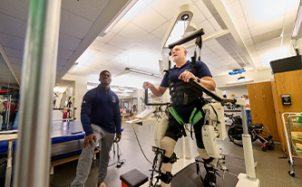 Male client works with exercise physiologist on walking while strapped into the Lokomat