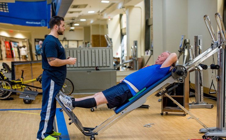 Male client lays in his back while using the Power Tower with his exercise physiologist.