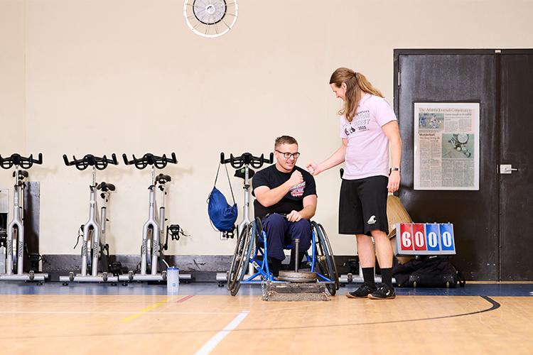 Andrew Corbett, Exercise Physiologist, works with Tyler Rogowski on a strength and conditioning program pulling a sled with a wheelchair.