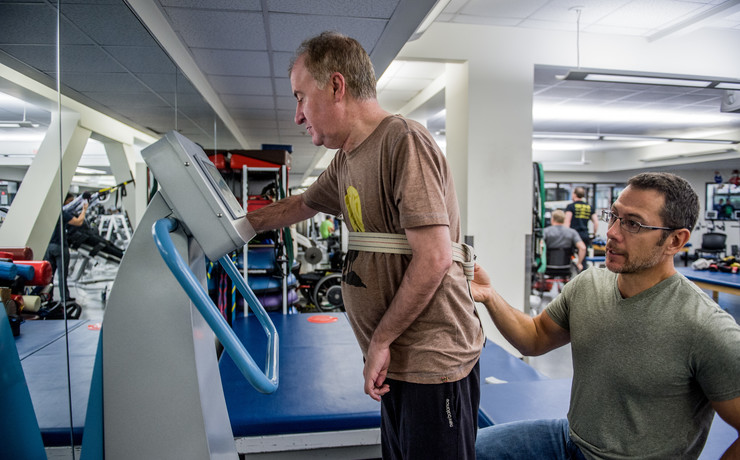 Male client being helped up by his exercise physiologist while using the WAVE vibration plate.