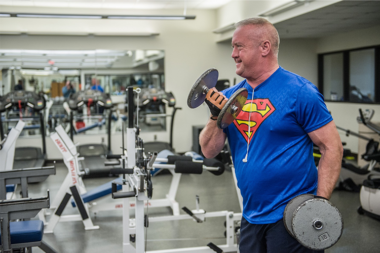 ProMotion member lifts heavy dumbbells inside the weight room