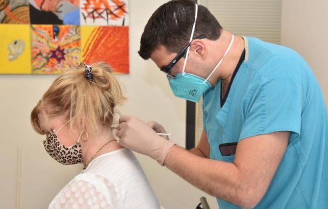 A Pain Institute physician injects a chronic pain treatment into the neck of a female patient