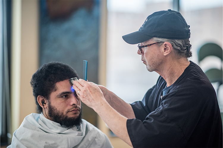 Shepherd Center volunteer gives a male patient a complimentary haircut.