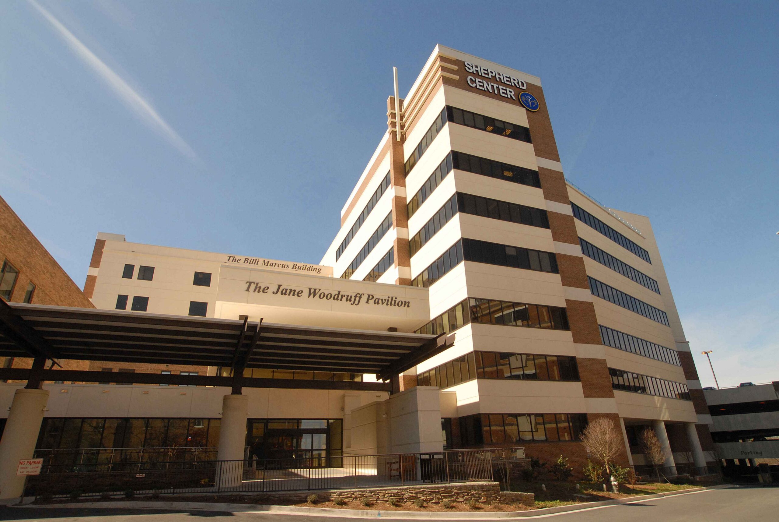 A modern hospital building under a clear blue sky, with the signage reading 