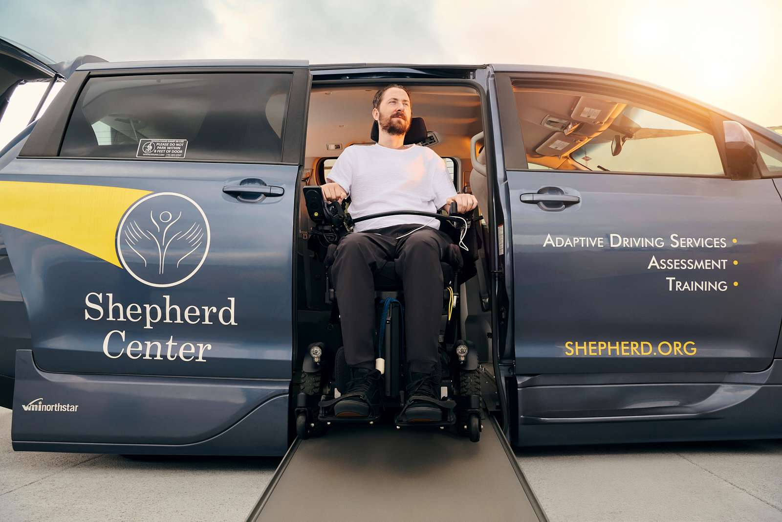 A man using a wheelchair is exiting a van with 