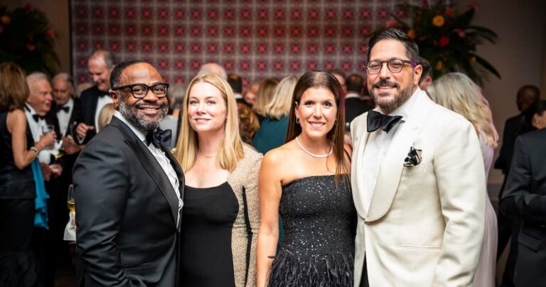 Four people posing for a photo at a formal event, including two men in tuxedos and two women in evening gowns.